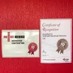 Certificate of recognition and approved contractor awarded to Airfield Electrical Services Ltd pinned up on red background